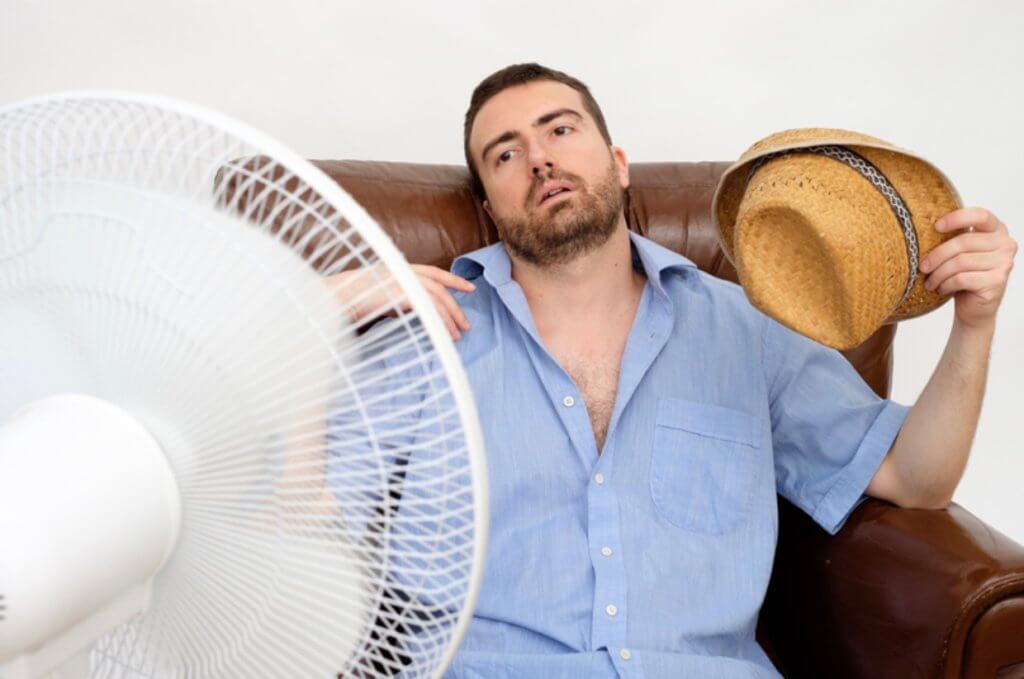 Man sitting in front of fan, trying to cool down.