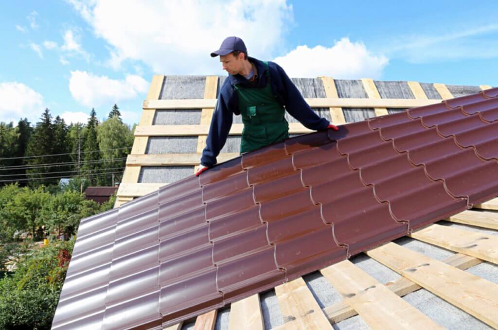Roofer installing long metal roofing panels
